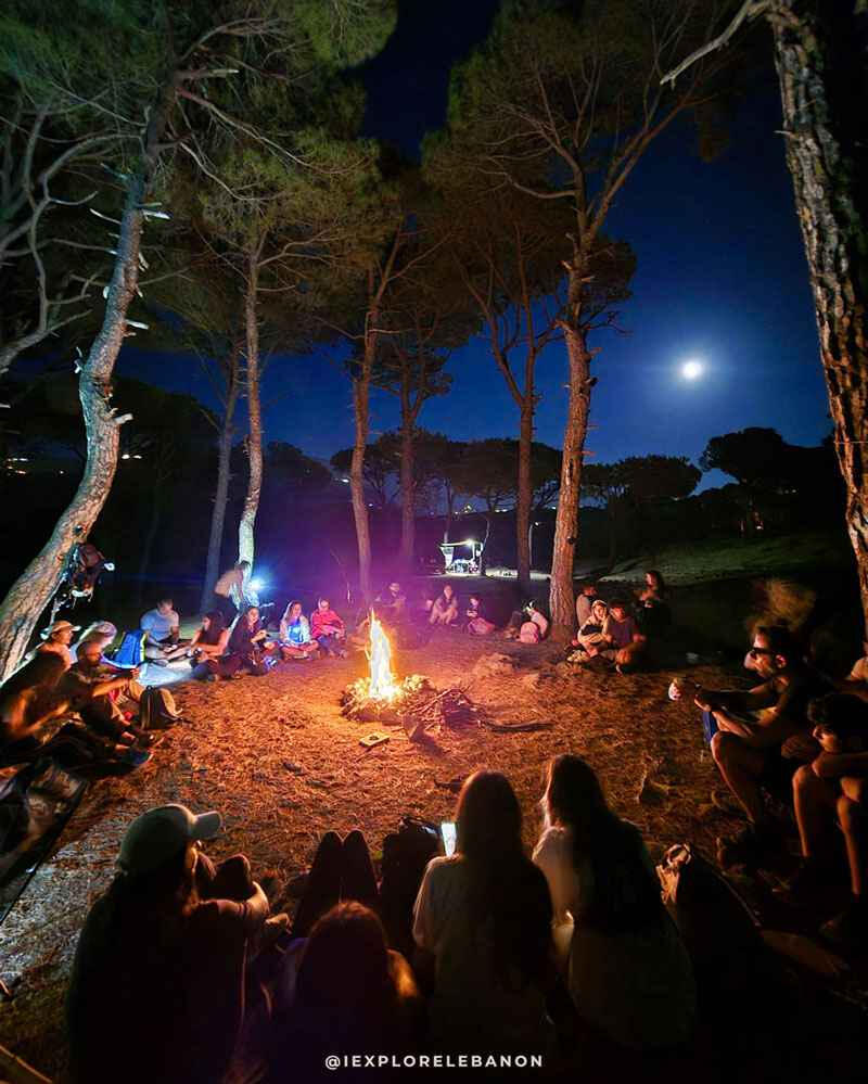 Camping bonfire at night in Lebanon with a group sitting under the moonlight and stargazing