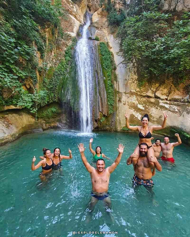 Group swimming under a waterfall in Lebanon during a summer hiking and river adventure